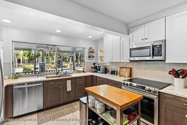 14 Bamboo Lane Jupiter, FL 33458 - Photo 16 of 33 a kitchen with stainless steel appliances granite countertop a stove top oven a sink dishwasher and a microwave oven with cabinets