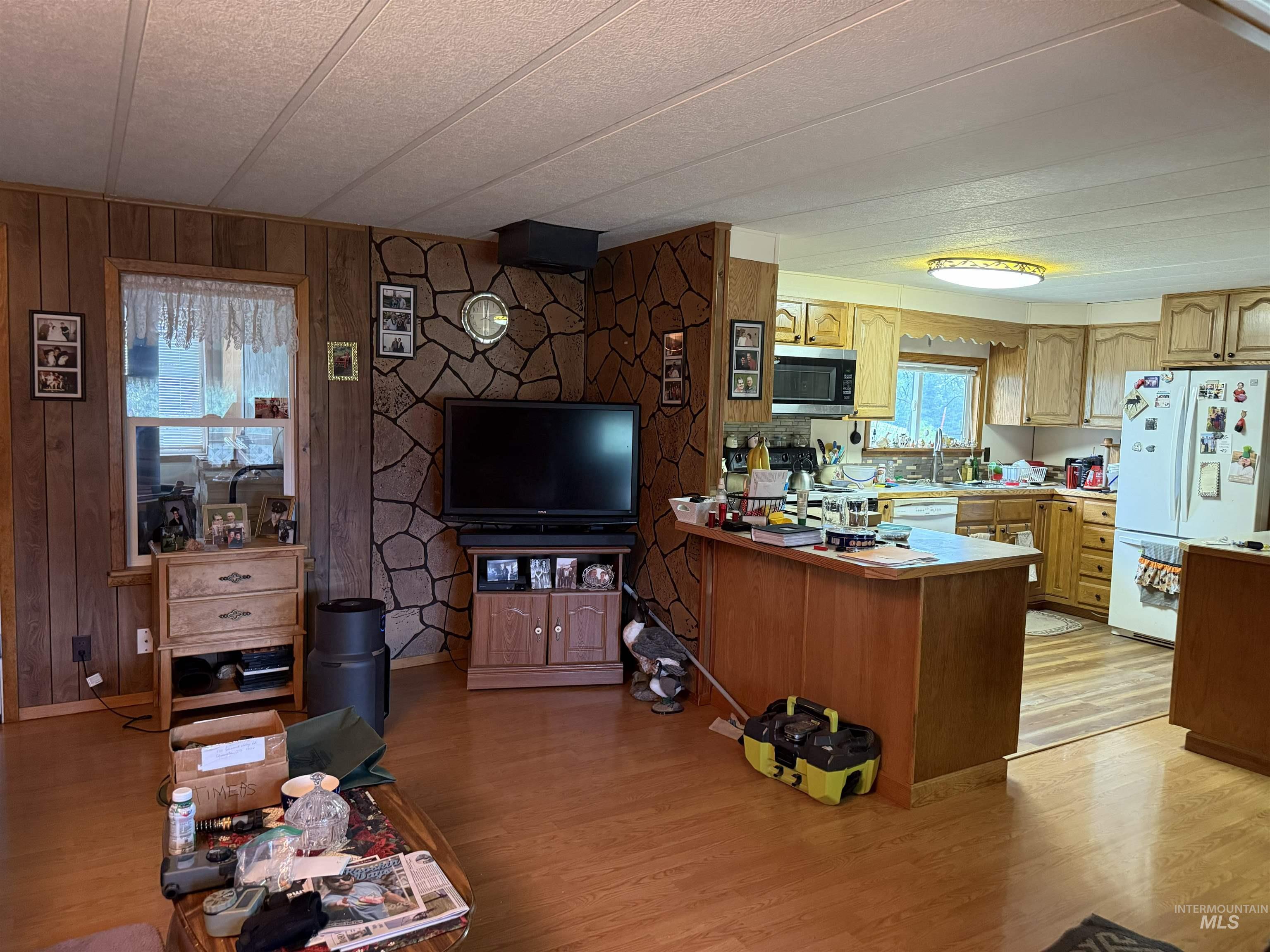 733 Pleasant Valley Road Stites, ID 83552 - Photo 11 of 46 Open-concept living space featuring wood-finish flooring, wood paneling, and a stone-accented wall