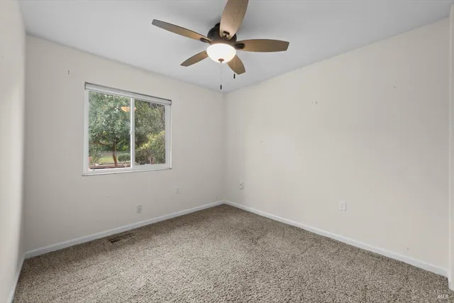 an empty room with a window and a fan