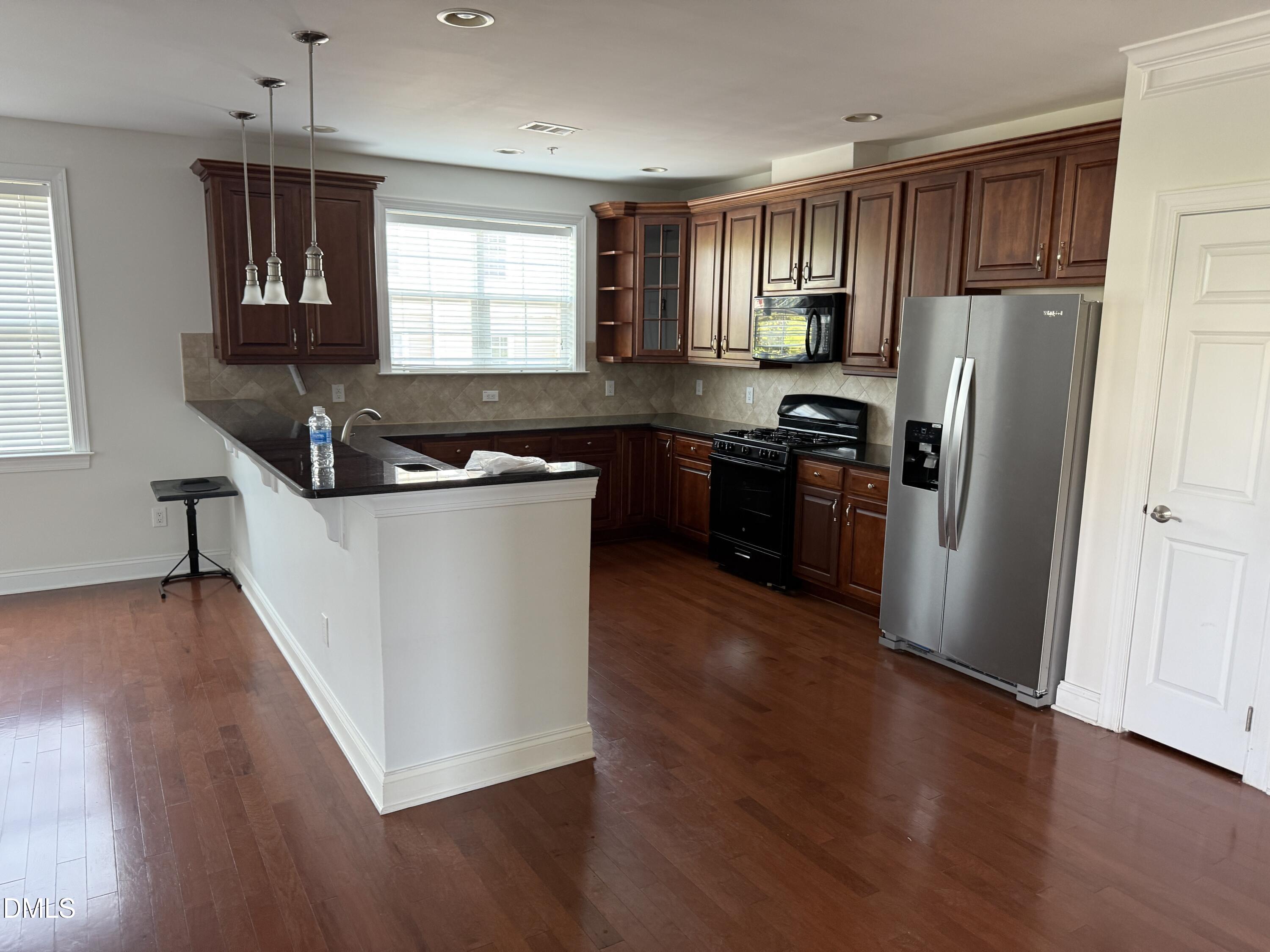 10511 Rosegate Court Raleigh, NC 27617 - Photo 23 of 26 a kitchen with stainless steel appliances granite countertop white cabinets a refrigerator a sink a stove a microwave and wooden floors