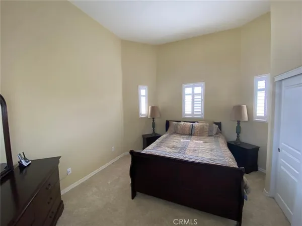 a bed sitting in a spacious bedroom and a mirror