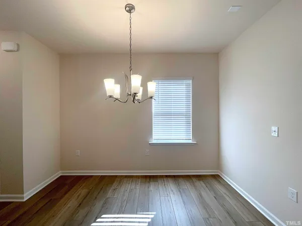 a view of empty room with wooden floor and chandelier