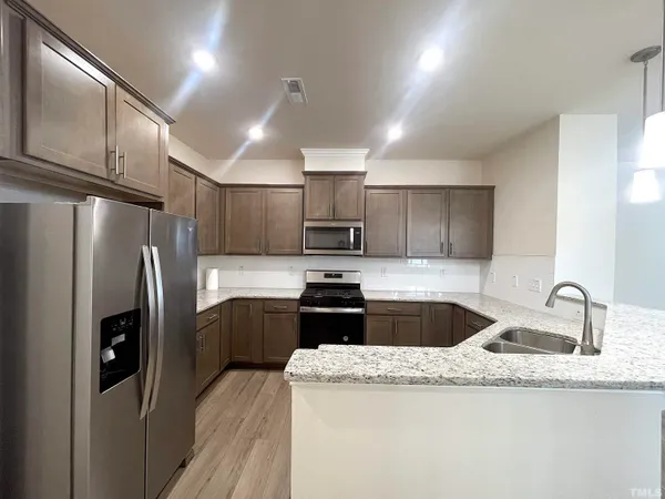 a kitchen with granite countertop a refrigerator sink and cabinets