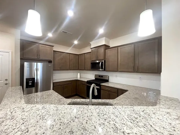 a kitchen with stainless steel appliances kitchen island granite countertop a sink a stove a microwave a refrigerator and cabinets