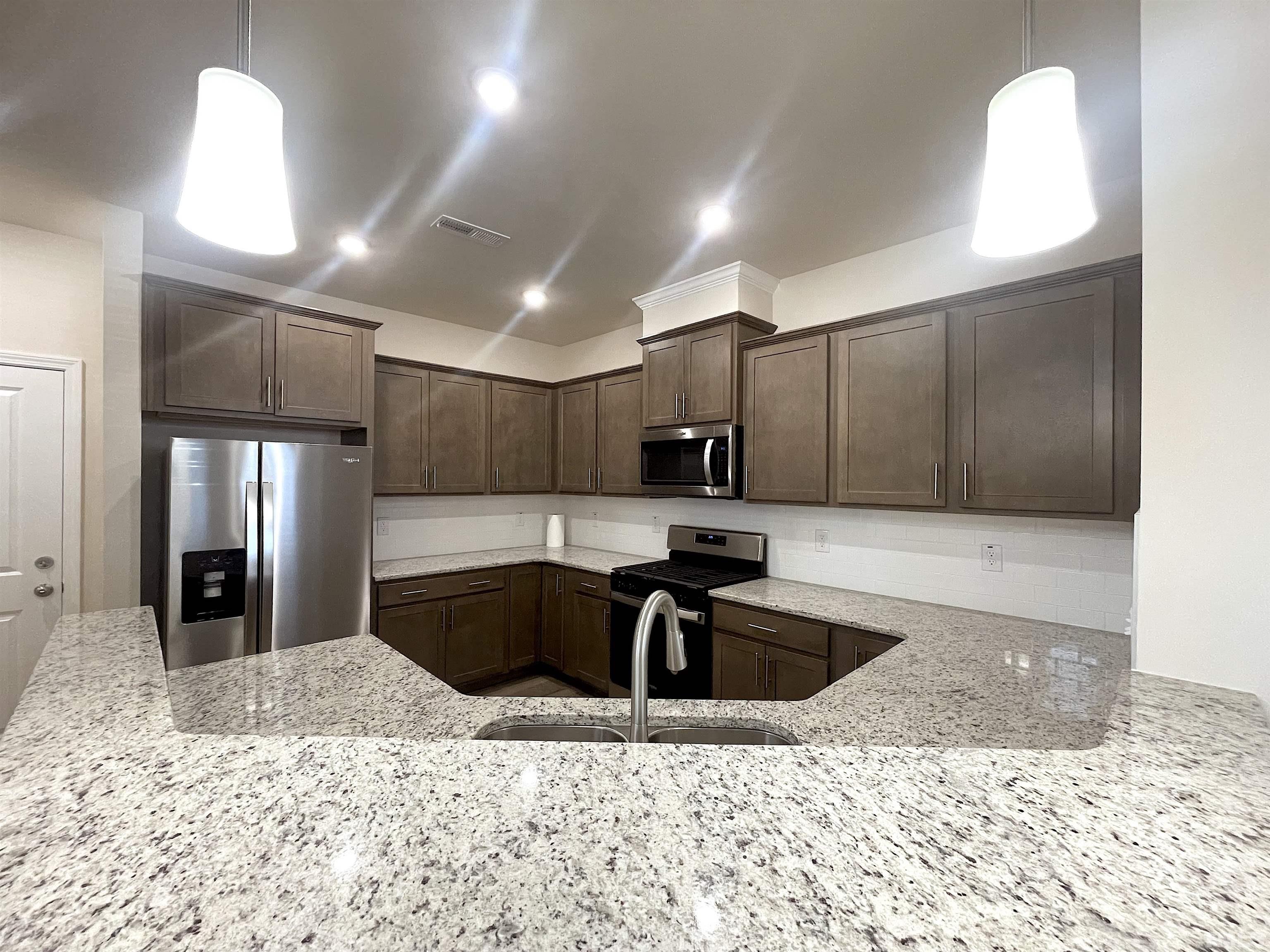 4906 Megara Run Raleigh, NC 27603 - Photo 9 of 30 a kitchen with stainless steel appliances kitchen island granite countertop a sink a stove a microwave a refrigerator and cabinets