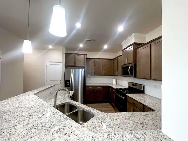 a kitchen with stainless steel appliances granite countertop a sink a stove and a refrigerator
