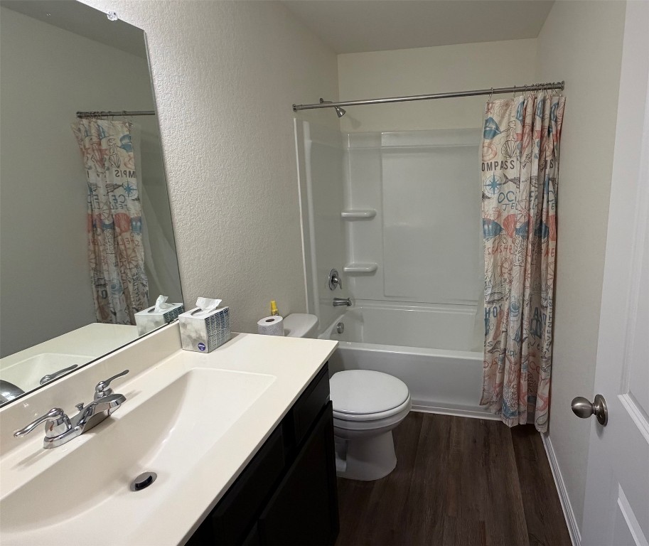 364 Bell Rings Drive Jarrell, TX 76537 - Photo 19 of 25 Bathroom with vanity, shower / bathtub combination with curtain, a textured wall, and dark wood finished floors