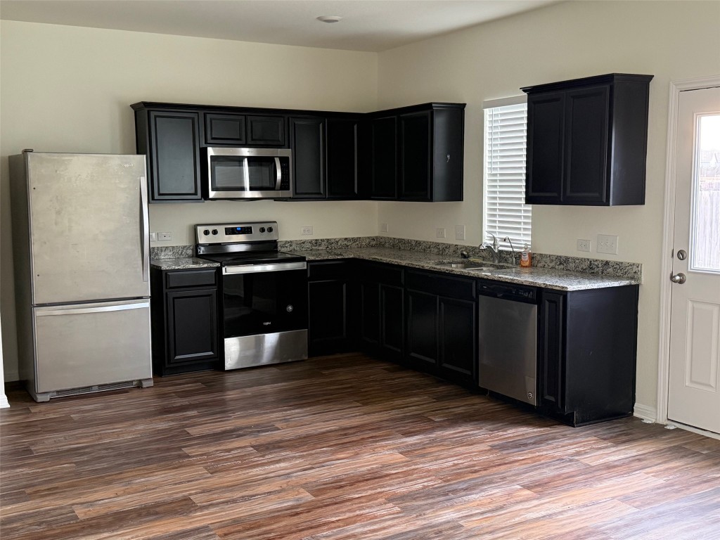 364 Bell Rings Drive Jarrell, TX 76537 - Photo 3 of 25 Kitchen featuring dark cabinetry, appliances with stainless steel finishes, dark stone counters, and dark wood finished floors