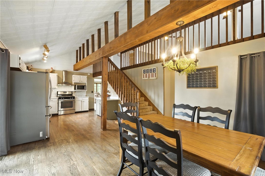 1371 Spider Ridge Road Parkersburg, WV 26104 - Photo 15 of 48 Dining area with light wood-type flooring, lofted ceiling, a chandelier, and stairs