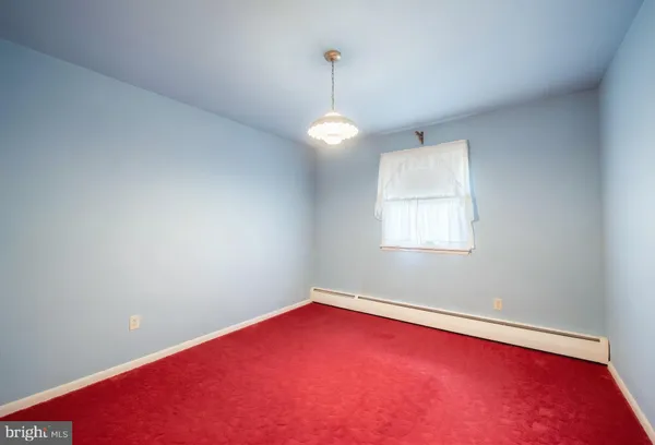 an empty room with chandelier fan and windows