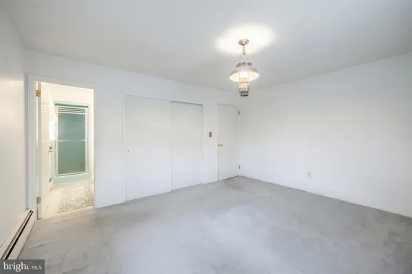 an empty room with a chandelier fan and a window