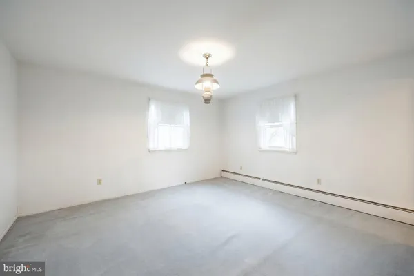 an empty room with a chandelier fan and windows
