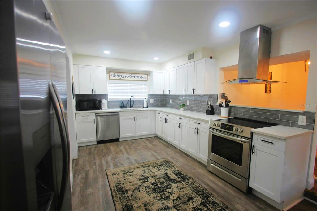6602 North 9th Street Tampa, FL 33604 - Photo 5 of 22 a kitchen with stainless steel appliances granite countertop a sink a stove a refrigerator and island with wooden floor