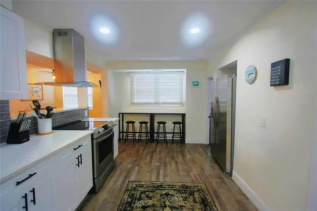 a kitchen with stainless steel appliances granite countertop a stove a sink dishwasher and a refrigerator with wooden floor