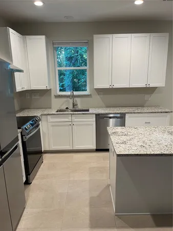 a kitchen with granite countertop a sink window and cabinets