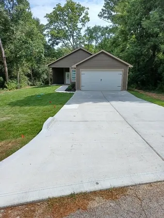 a view of a house with a yard and large tree