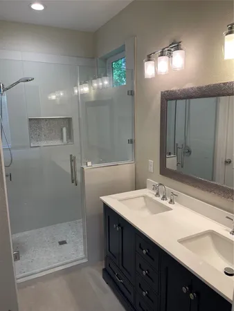 a bathroom with a double vanity sink mirror and shower
