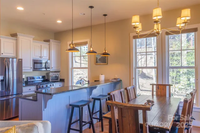a kitchen with stainless steel appliances wooden floor dining table and chairs
