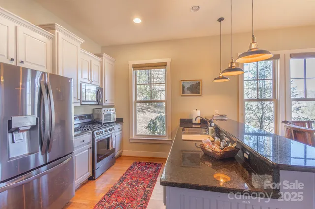 a kitchen with stainless steel appliances granite countertop a refrigerator a stove and a sink with wooden floor