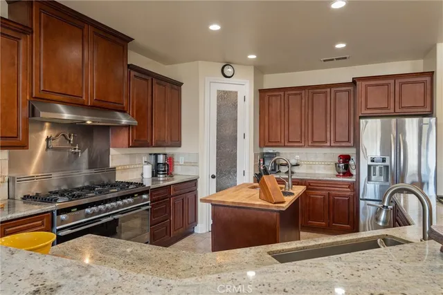 a kitchen with stainless steel appliances granite countertop a stove refrigerator and cabinets