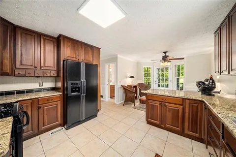 a kitchen with stainless steel appliances granite countertop a refrigerator a sink dishwasher a stove with white cabinets and wooden floor