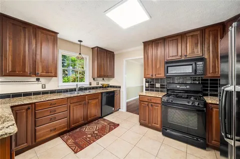 a kitchen with granite countertop wooden cabinets stainless steel appliances and a window