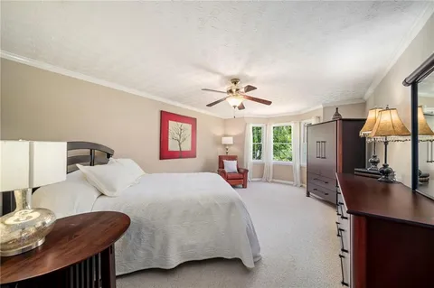 a bedroom with a bed a large window and mirror