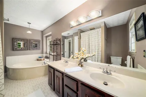 a bathroom with a double vanity sink mirror and bathtub