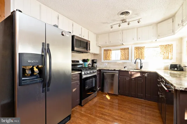 a kitchen with stainless steel appliances granite countertop a sink and wooden cabinets