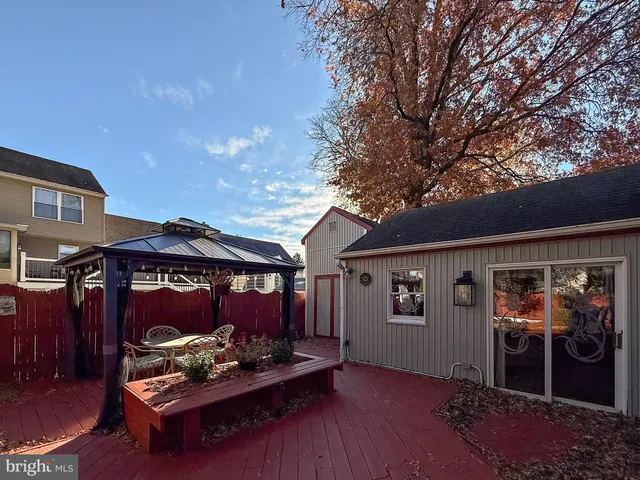 a backyard of a house with table and chairs under an umbrella