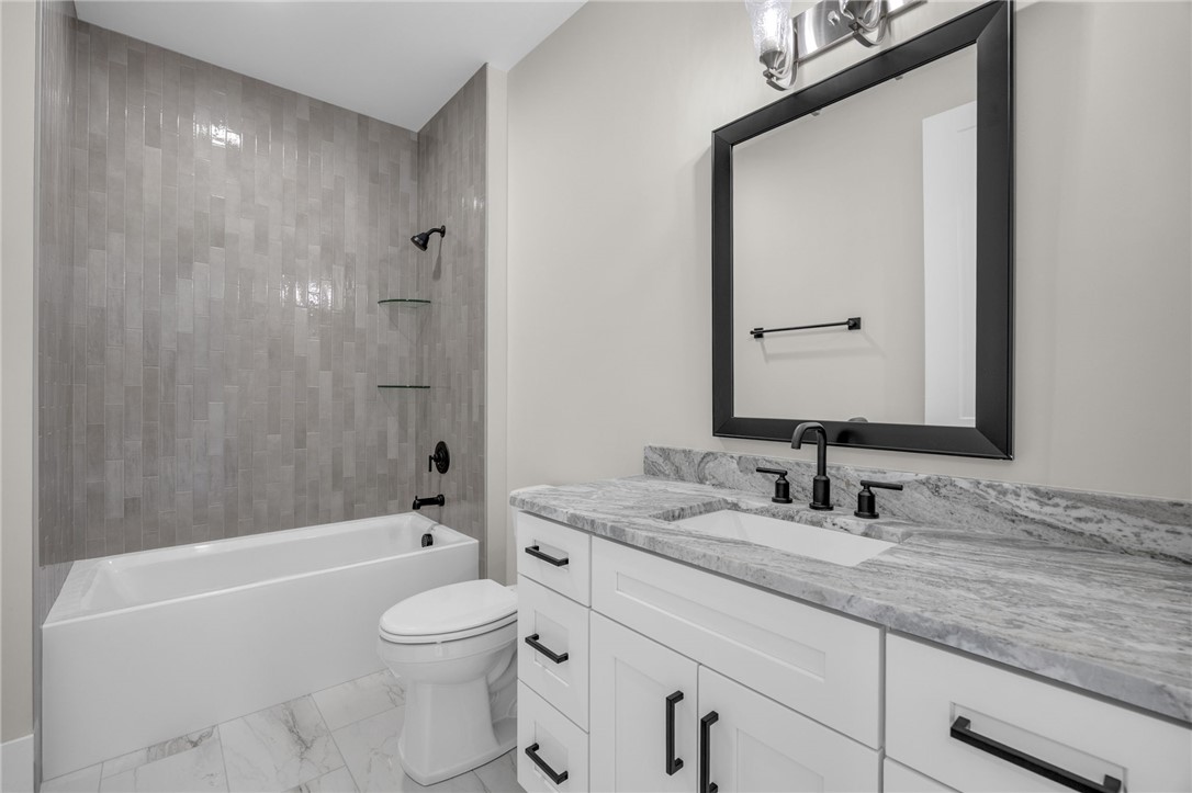 1230 Melton Road, Unit 216 West Union, SC 29696 - Photo 18 of 49 Modern bathroom featuring sleek tiled walls, a pristine white tub, and a vanity with a marbled countertop.