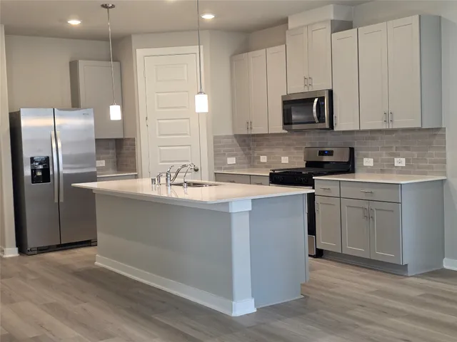 a kitchen with stainless steel appliances a sink a stove a microwave a sink a refrigerator and cabinets