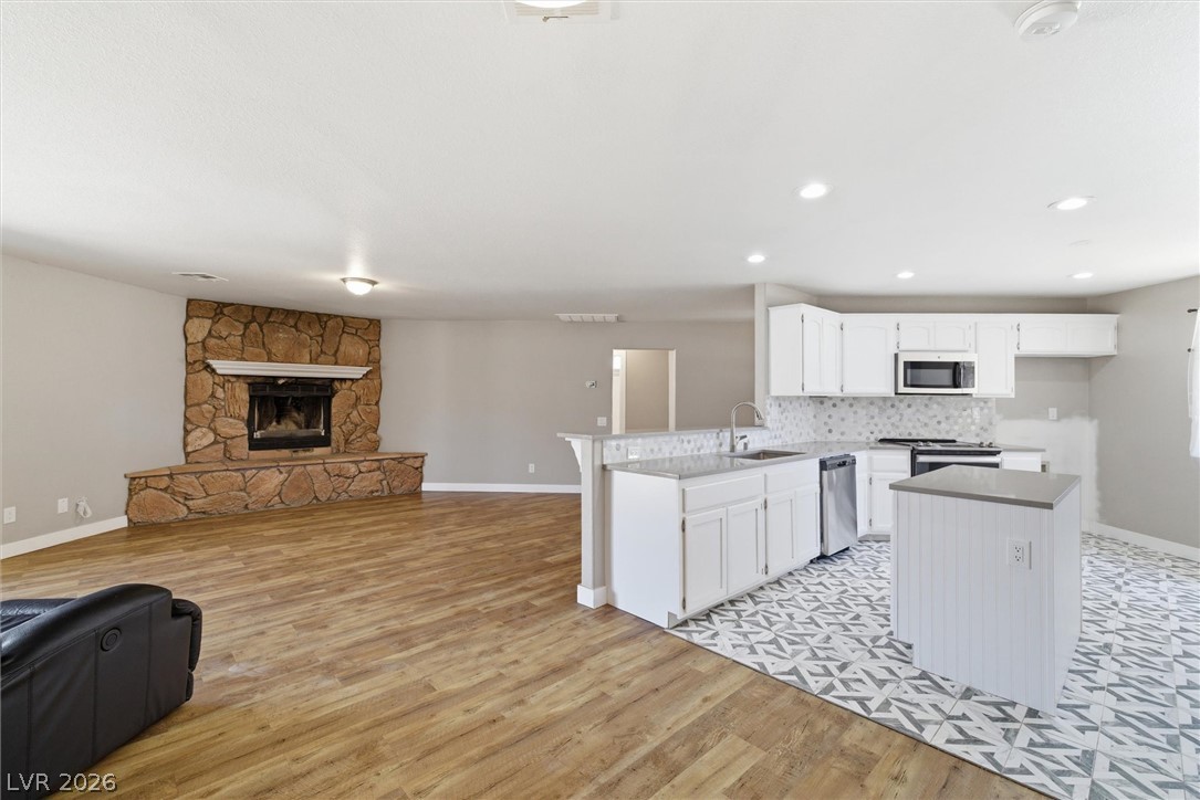 2780 West Simkins Road Pahrump, NV 89060 - Photo 13 of 40 A striking stone fireplace anchors this spacious room, complementing the sleek, modern kitchen with its unique patterned tile.