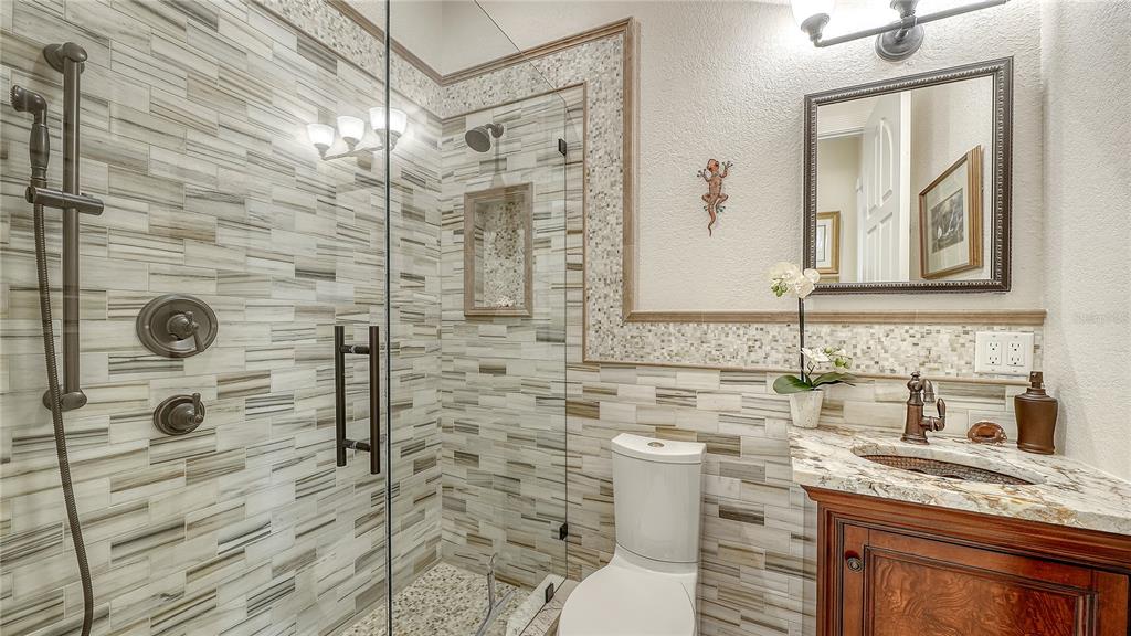 1630 Assisi Drive, Unit 18 Sarasota, FL 34231 - Photo 19 of 42 a bathroom with a granite countertop sink a toilet a mirror and shower