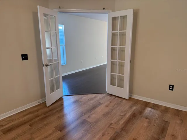 an empty room with wooden floor and windows