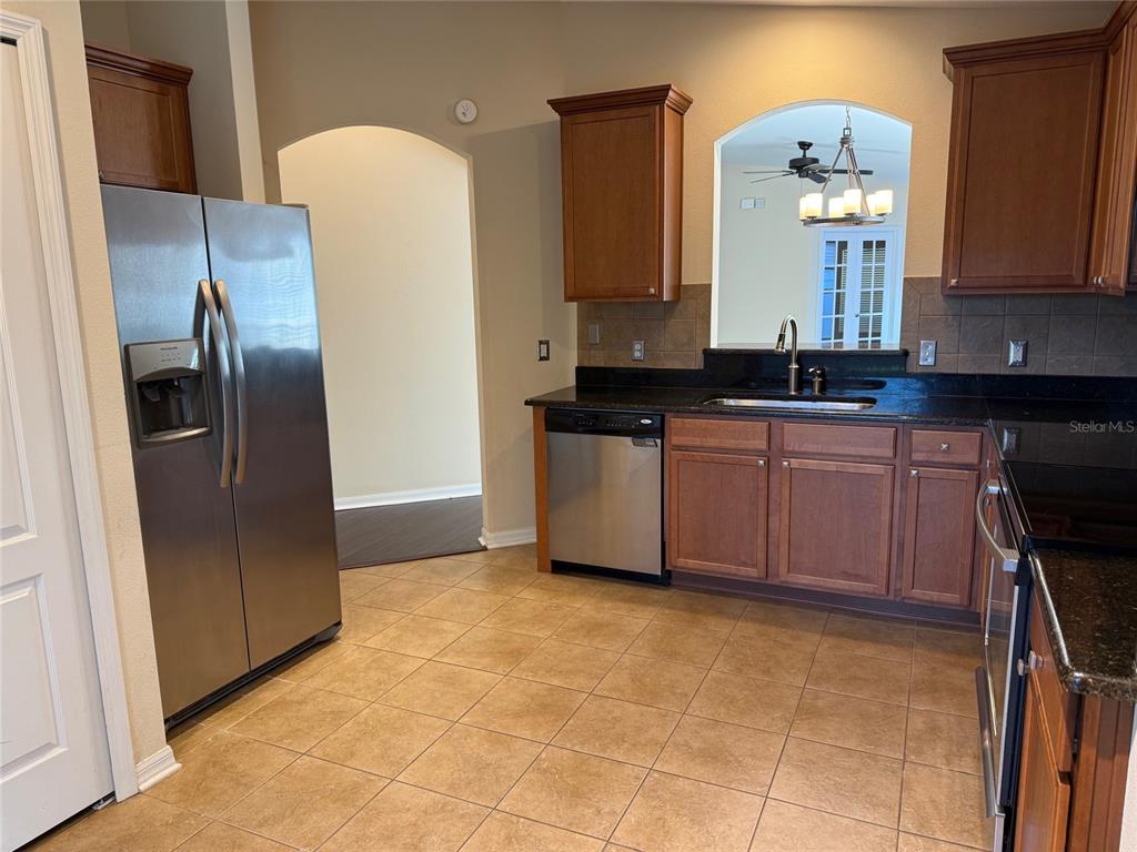 12311 Boot Spur Way Spring Hill, FL 34610 - Photo 8 of 25 a hall with stainless steel appliances granite countertop a sink refrigerator and cabinets