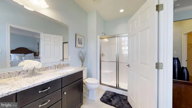 a bathroom with a granite countertop sink a toilet and shower