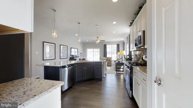 a kitchen with stainless steel appliances kitchen island granite countertop a stove refrigerator and cabinets