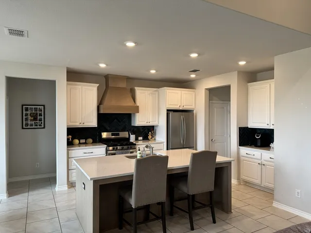 a kitchen with a sink a microwave a refrigerator and chairs