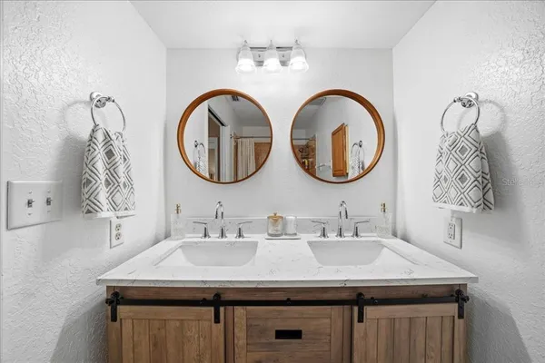 a bathroom with a granite countertop double vanity sink and a mirror