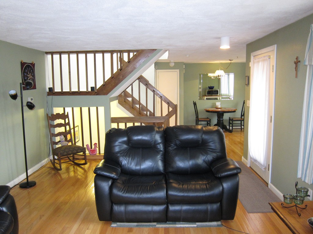 136 Mountain Gate Road, Unit 136 Ashland, MA 01721 - Photo 4 of 23 a living room with a couch and a dining table with wooden floor