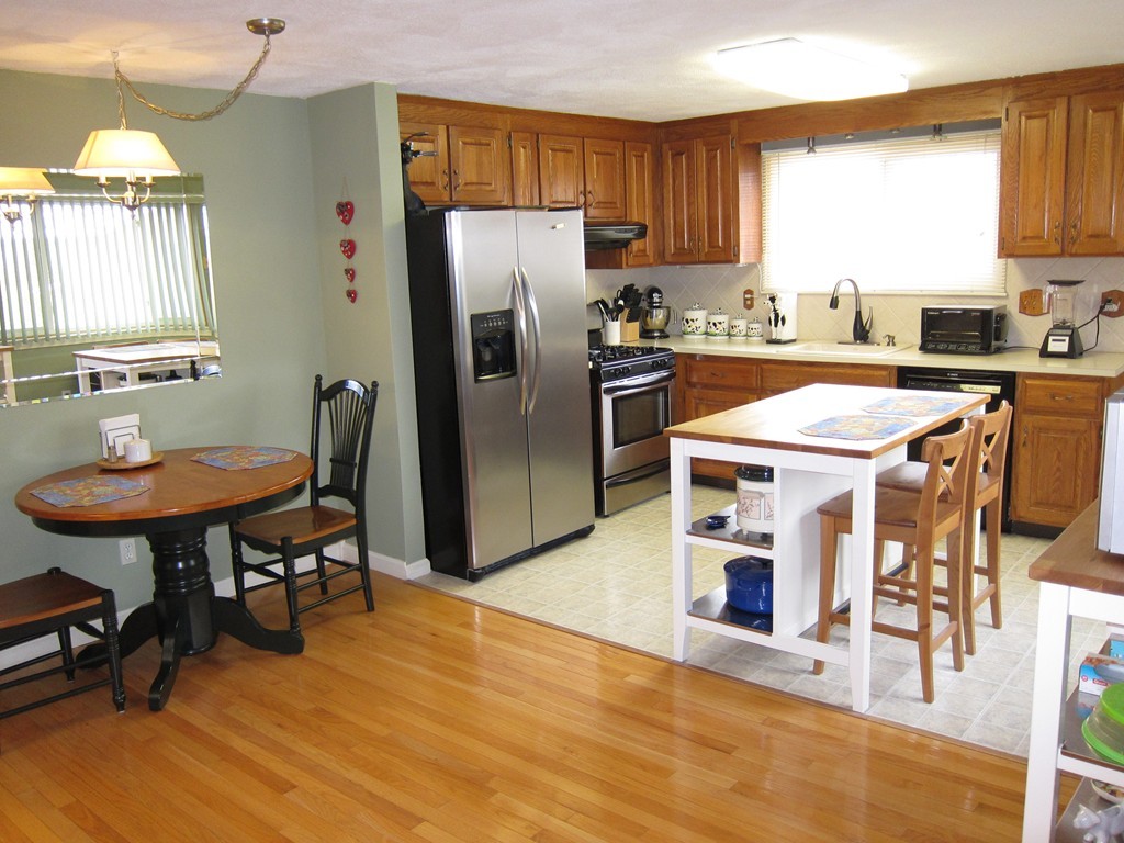 136 Mountain Gate Road, Unit 136 Ashland, MA 01721 - Photo 5 of 23 a kitchen with stainless steel appliances a dining table chairs refrigerator and sink