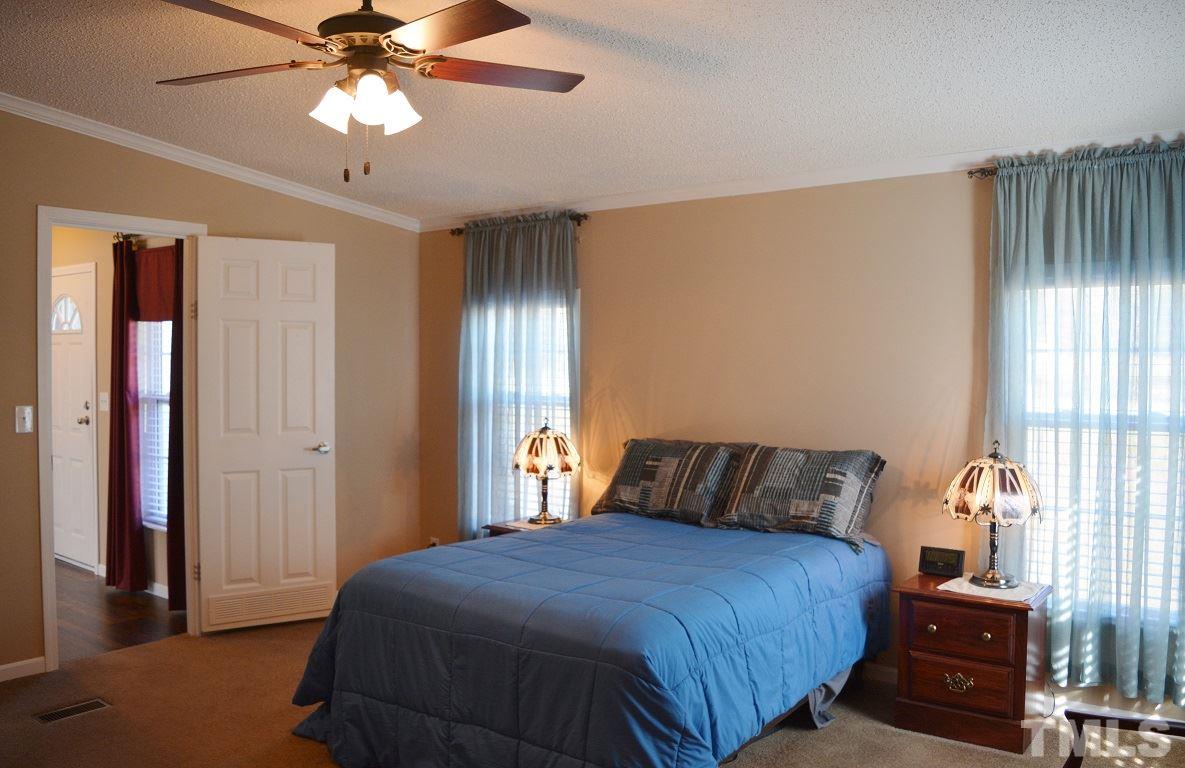 747 Glover Road Dunn, NC 28334 - Photo 9 of 25 a bedroom with a bed and a chandelier