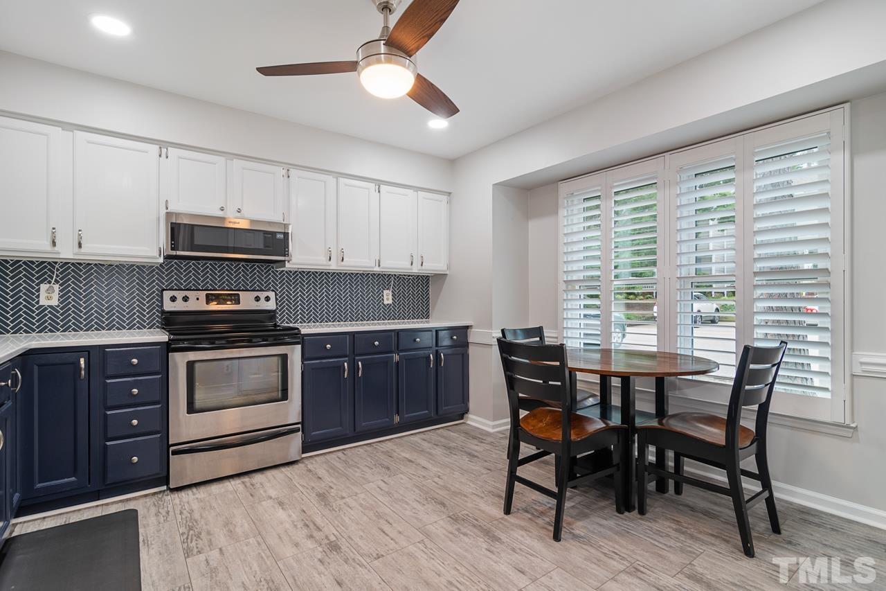 1426 Mapleside Court Raleigh, NC 27609 - Photo 10 of 38 a kitchen with a stove a sink dishwasher a dining table and chairs with wooden floor