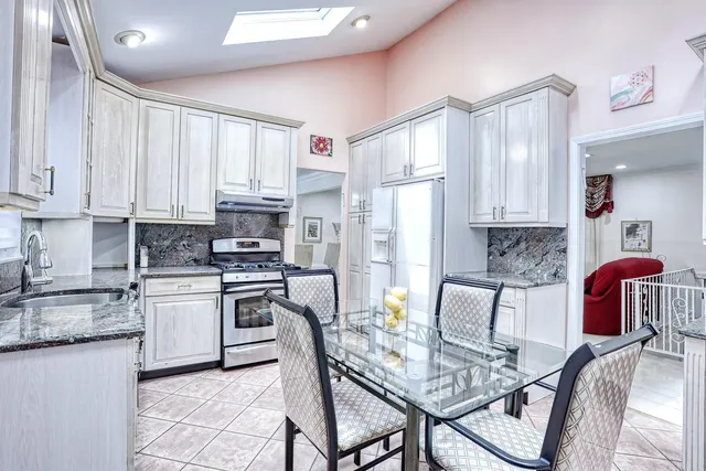 a kitchen with stainless steel appliances granite countertop a stove a sink dishwasher a refrigerator with white cabinets and wooden floor