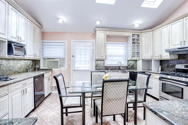 a kitchen with granite countertop white cabinets and stainless steel appliances