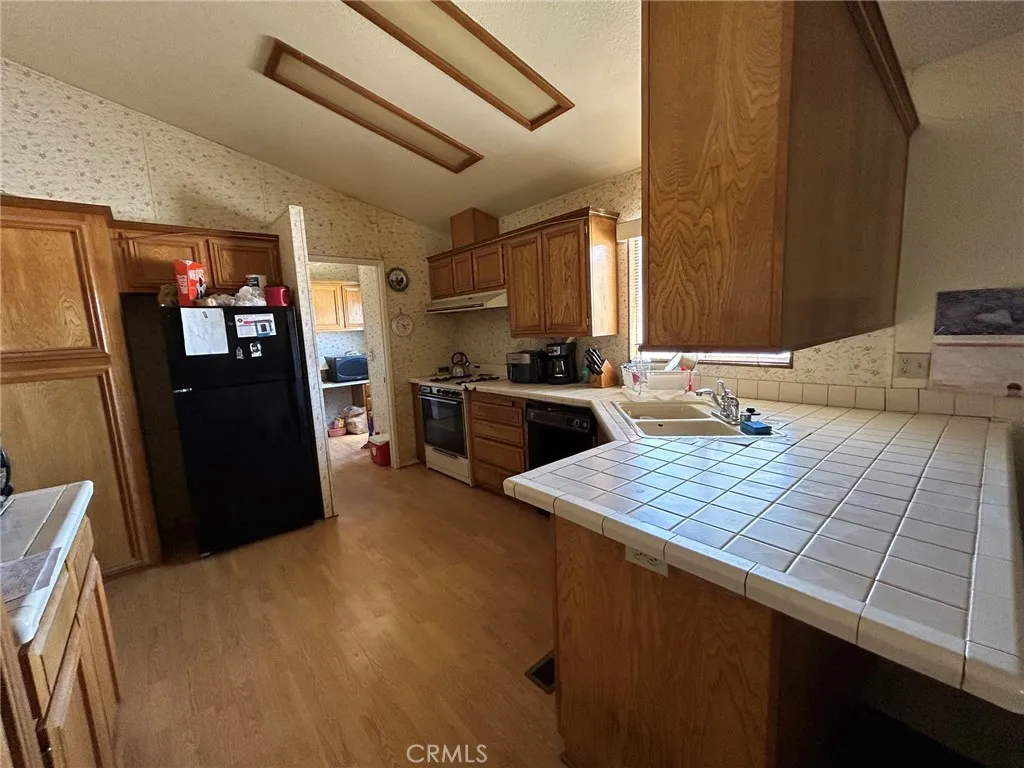 27250 Murrieta Road, Unit 347 Menifee, CA 92586 - Photo 6 of 38 a kitchen with a sink dishwasher a refrigerator a stove and a dining table with wooden cabinet