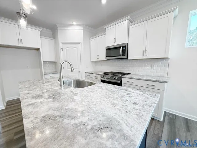 a kitchen with stainless steel appliances a sink a stove a microwave a sink a refrigerator and cabinets