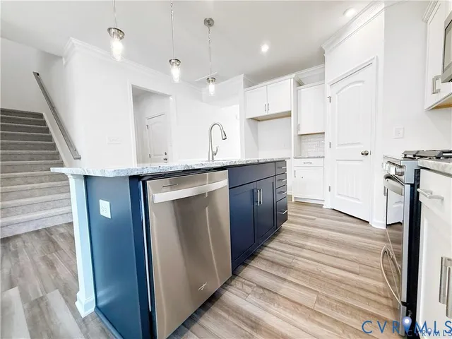 a large kitchen with stainless steel appliances granite countertop a lot of counter space and wooden floors