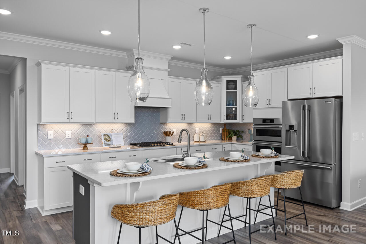 297 Crop Road Angier, NC 27501 - Photo 11 of 23 a kitchen with stainless steel appliances granite countertop a sink a stove a refrigerator and white cabinets with wooden floor